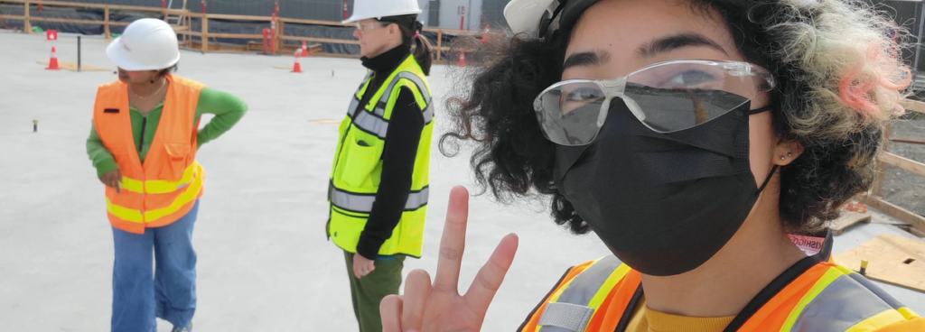 戴口罩的学生在建筑工地举着和平标志